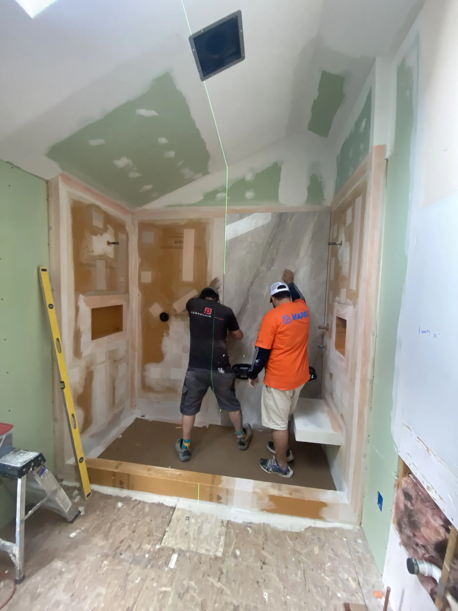 A Benchmark crew member setting custom tile in a Seacoast bathroom shower
