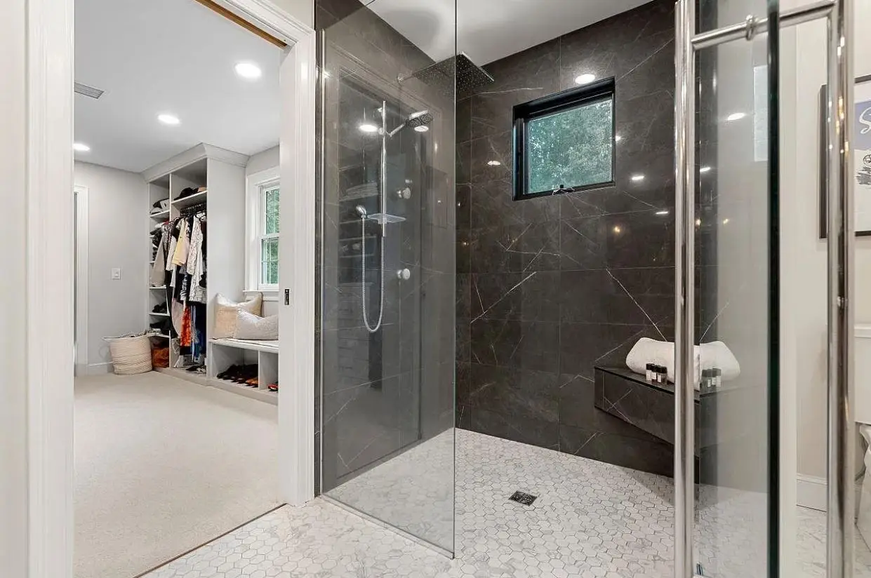 Bathroom design inspiration: a curbless walk-in shower in charcoal large-format tile with a floating bench and a hex marble mosaic floor
