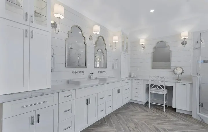 White bathroom with a double vanity, arched mirrors, and polished chrome fixtures, remodeled by Benchmark on the New Hampshire Seacoast
