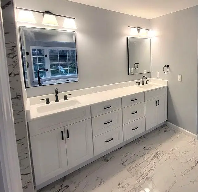 White double-vanity bathroom with black fixtures and marble-look tile floor, remodeled by Benchmark on the New Hampshire Seacoast