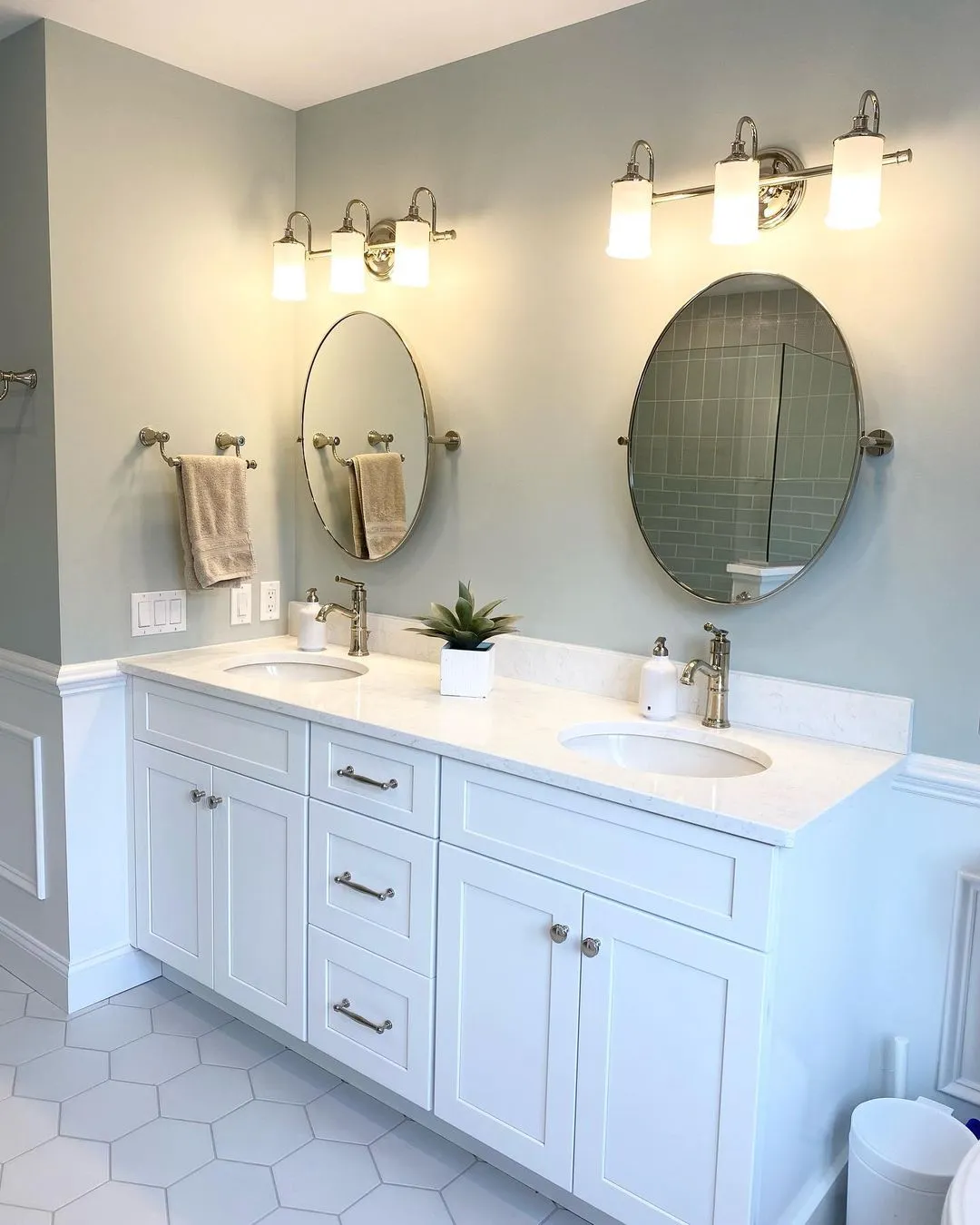 Bathroom with a double vanity, oval mirrors, and sage-green walls, remodeled by Benchmark on the New Hampshire Seacoast