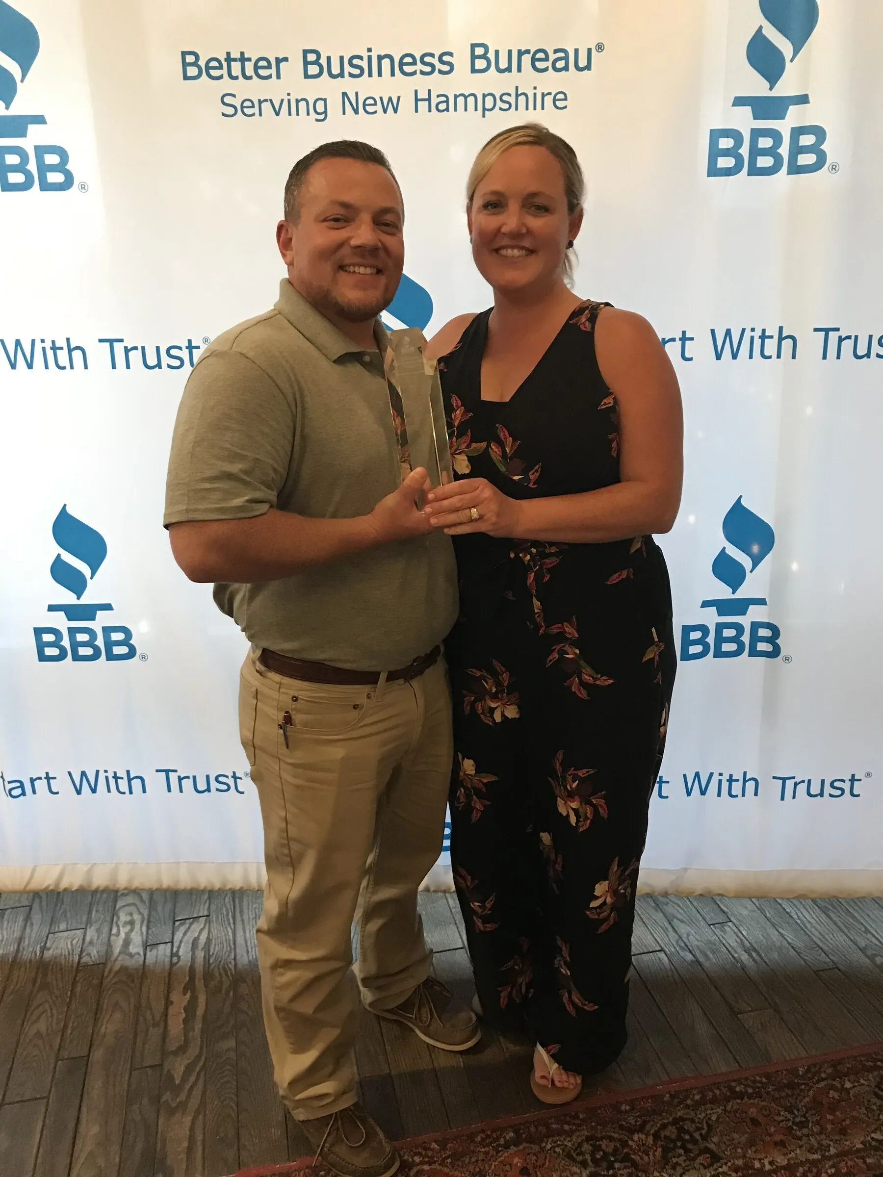 Lee Veader Sr. and co-owner Meoghan Veader holding Benchmark's 2018 Better Business Bureau Torch Award trophy at the BBB of New Hampshire
