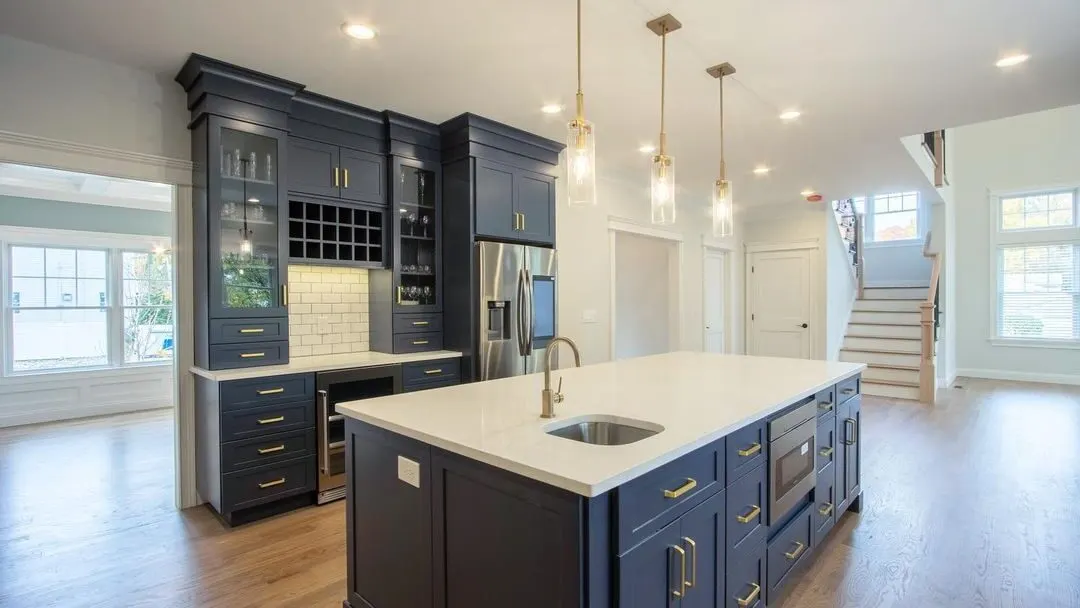 A remodeled navy kitchen with gold hardware and a white quartz island in a Seacoast New Hampshire home by Benchmark