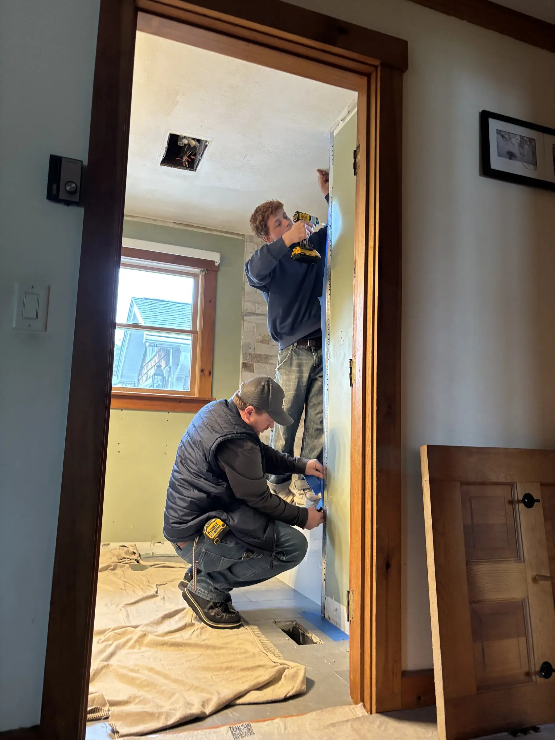 Benchmark crew prepping and waterproofing a bathroom doorway and walls during a Seacoast NH remodel
