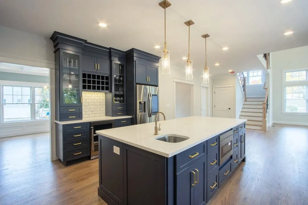 Navy kitchen cabinets with gold hardware and a white quartz island, remodeled by Benchmark Home Improvements on the New Hampshire Seacoast