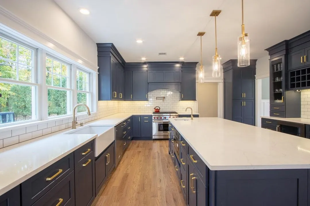 Navy-blue kitchen remodel with a large quartz-topped island, brass hardware, and a white subway tile backsplash, by Benchmark Home Improvements serving Dover, NH