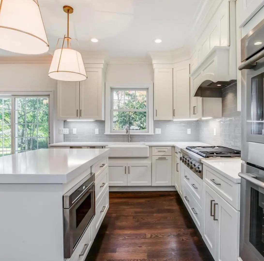 White kitchen with a farmhouse sink and dark hardwood floors, remodeled by Benchmark on the New Hampshire Seacoast