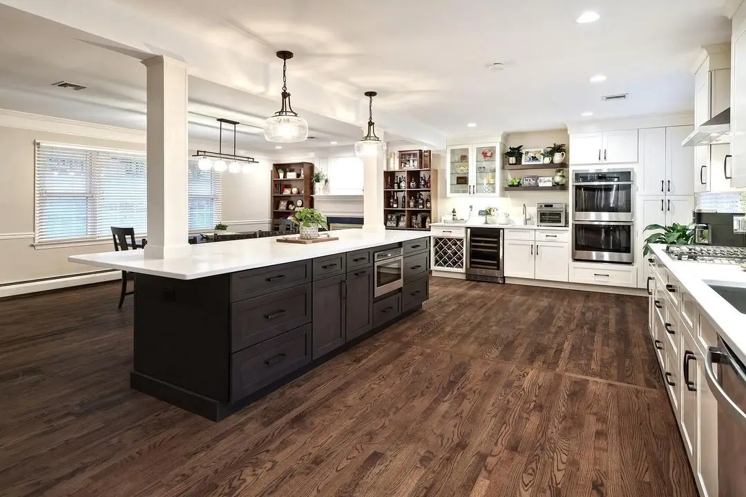 Open-concept kitchen with a dark island and white quartz countertops, remodeled by Benchmark on the New Hampshire Seacoast