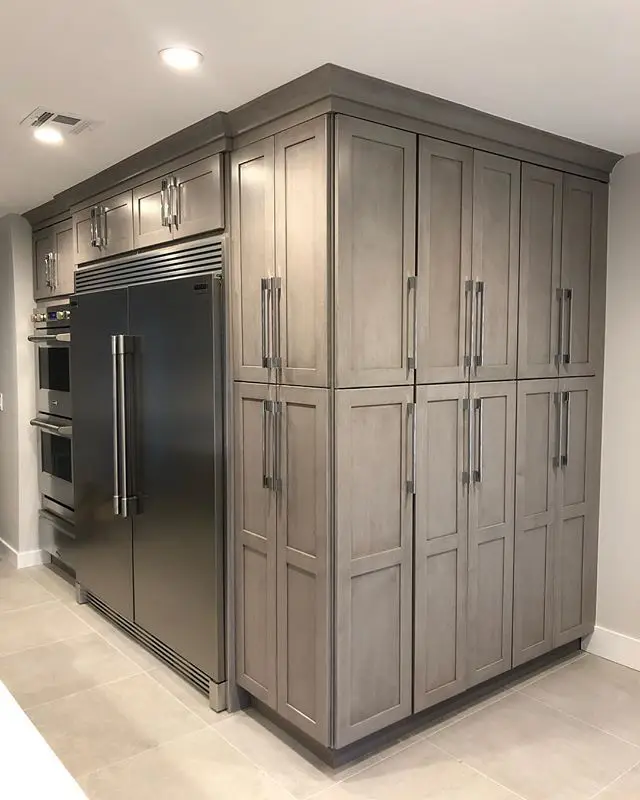 Grey-stained shaker kitchen with a built-in refrigerator and stainless double wall ovens, remodeled by Benchmark on the New Hampshire Seacoast