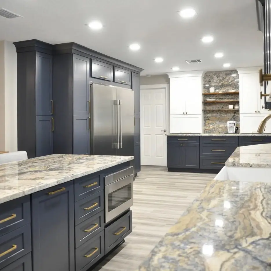Navy kitchen with granite waterfall islands and gold fixtures, remodeled by Benchmark on the New Hampshire Seacoast
